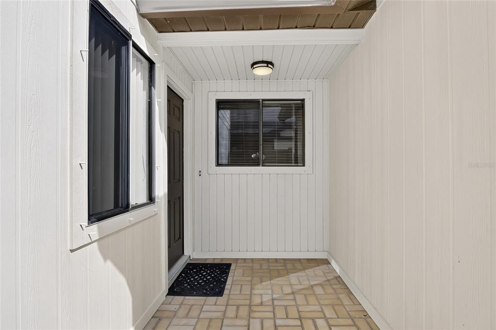 A covered entryway features vertical white siding, a dark front door, and a tiled floor — 367 CASTLEWOOD LANE, NEW SMYRNA BEACH, FL