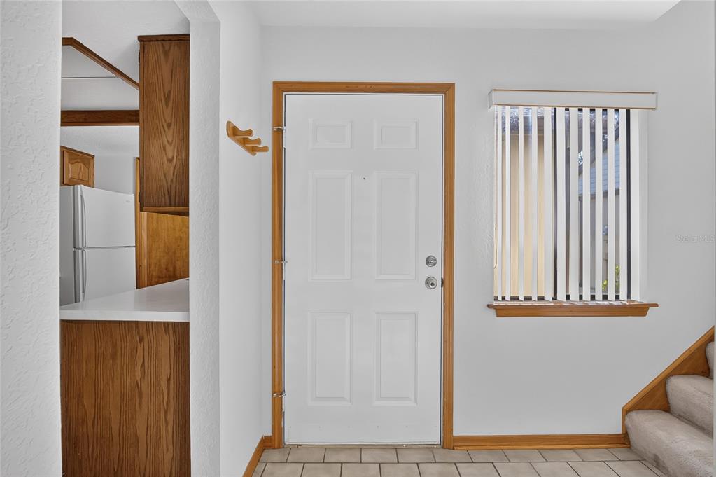An entryway features a white front door, tile flooring, a window with blinds, and stairs — 367 CASTLEWOOD LANE, NEW SMYRNA BEACH, FL