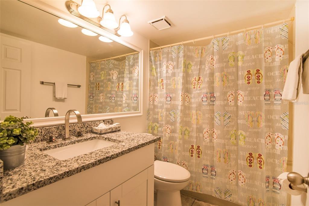 A bathroom features a granite vanity, a white sink, and a beach-themed shower curtain — 4601 46TH STREET COURT W UNIT 103B, BRADENTON, FL