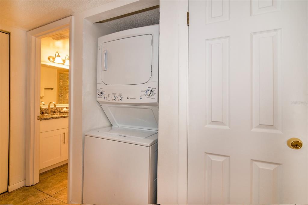A stacked washer and dryer unit is located in a hallway next to a bathroom — 4601 46TH STREET COURT W UNIT 103B, BRADENTON, FL