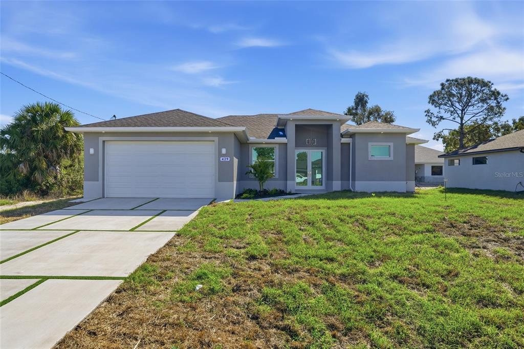 A single-story house with a two-car garage, gray stucco exterior, and a concrete driveway — 429 PALMYRA AVENUE, LEHIGH ACRES, FL