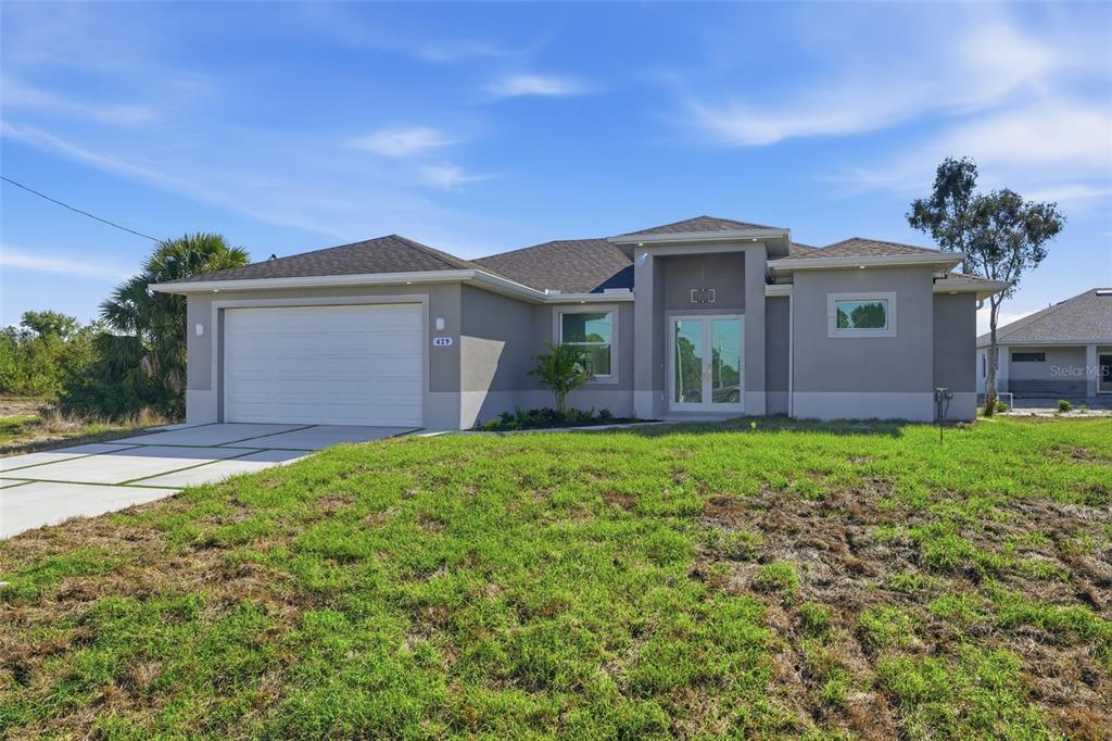 A single-story house with a gray stucco exterior, a two-car garage, and a grass lawn — 429 PALMYRA AVENUE, LEHIGH ACRES, FL