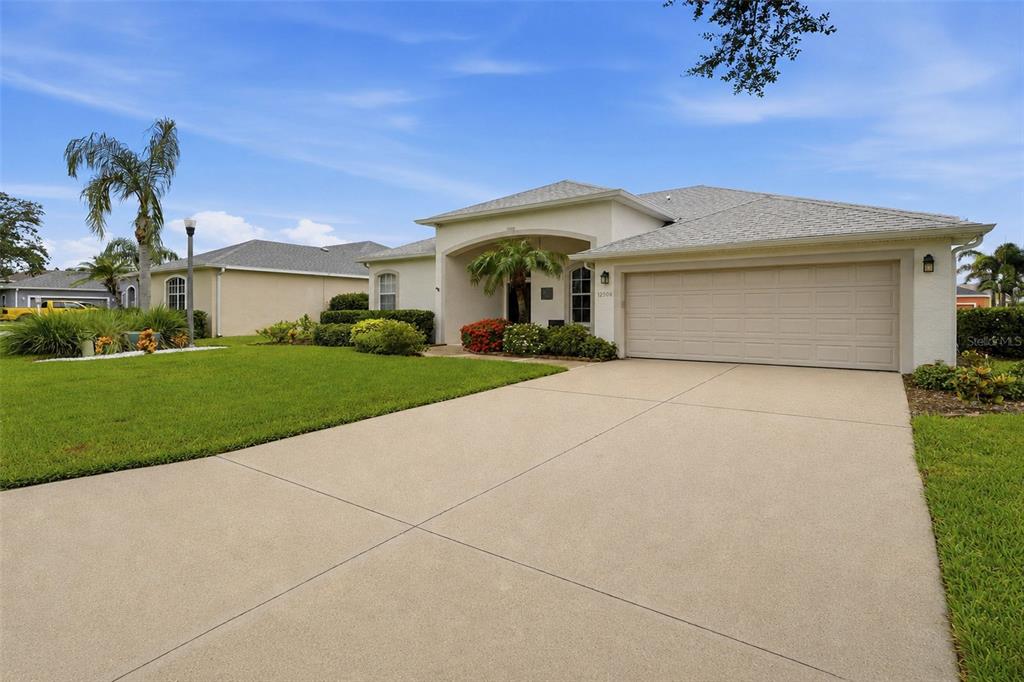 A covered front porch features a dark brown door, a window, and two wicker chairs — 12506 25TH COURT E, PARRISH, FL