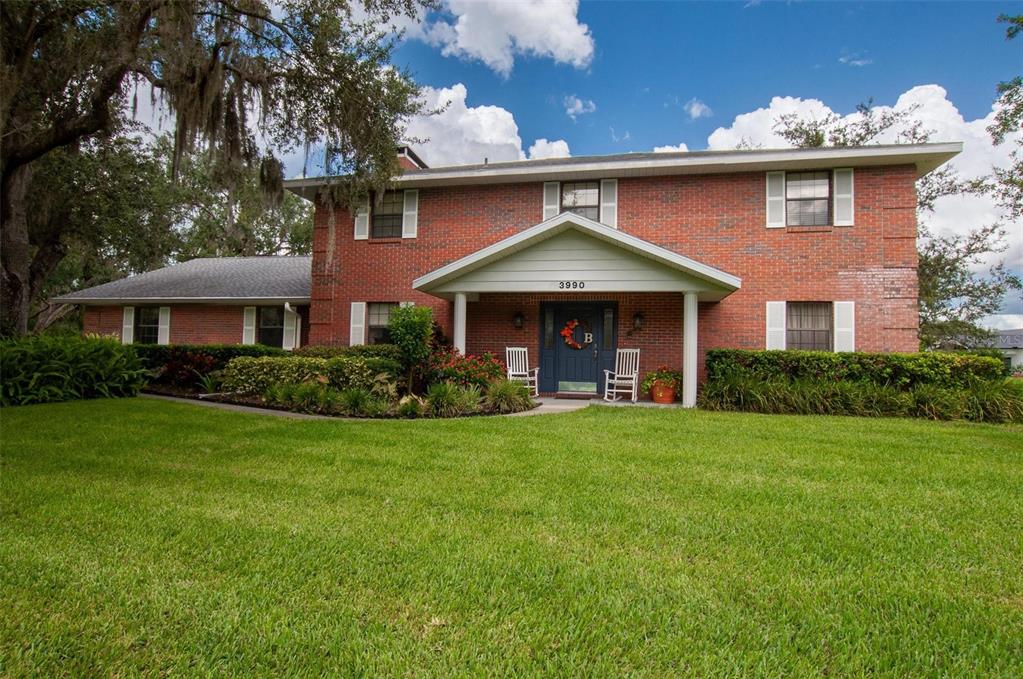 A two-story red brick house features a covered front porch and white window shutters — 3990 NE ASHLEY TERRACE, ARCADIA, FL