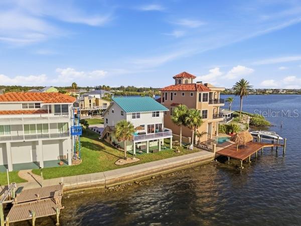 An aerial view shows three waterfront houses along a seawall with private docks and palm trees — 6421 DRIFTWOOD DRIVE, HUDSON, FL