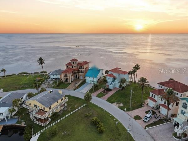 An aerial view shows several coastal houses along a road overlooking the ocean at sunset — 6421 DRIFTWOOD DRIVE, HUDSON, FL