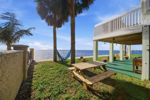A wooden picnic table sits on a grassy lawn beneath palm trees near the water — 6421 DRIFTWOOD DRIVE, HUDSON, FL