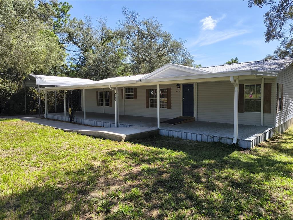 A single-story house with light siding, a metal roof, and a wide covered front porch — 4703 S HATTERAY POINT, LECANTO, FL