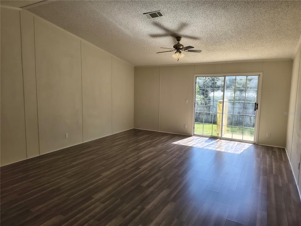 An empty room with wood-look flooring, a ceiling fan, and sliding glass doors to outside — 4703 S HATTERAY POINT, LECANTO, FL