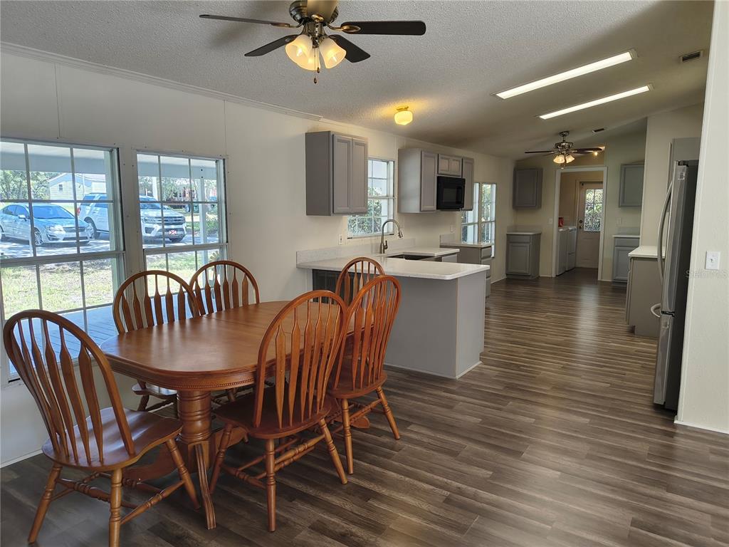 A dining area with a wooden table and chairs adjacent to a kitchen with grey cabinets — 4703 S HATTERAY POINT, LECANTO, FL