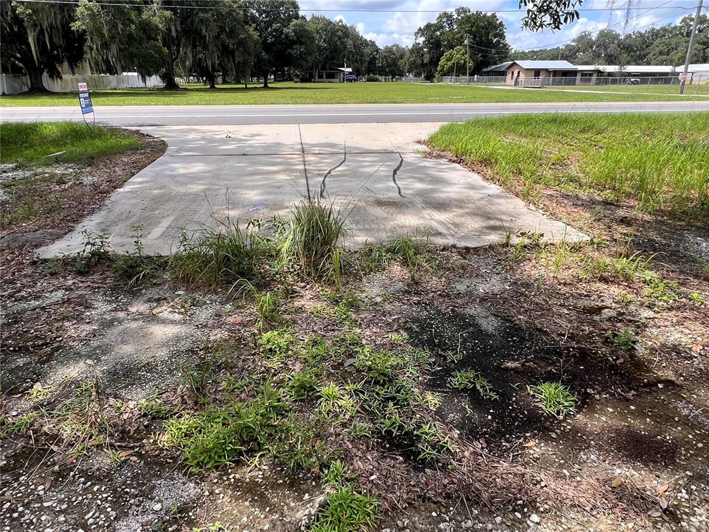 A concrete driveway pad sits in front of a grassy lot with a road beyond — US HIGHWAY 98 W, FROSTPROOF, FL