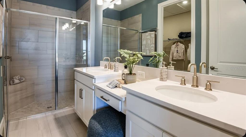 A kitchen features white cabinets, stainless steel appliances, a farmhouse sink, and wood-look tile flooring — 5380 SPOONFLOWER COURT, ST CLOUD, FL