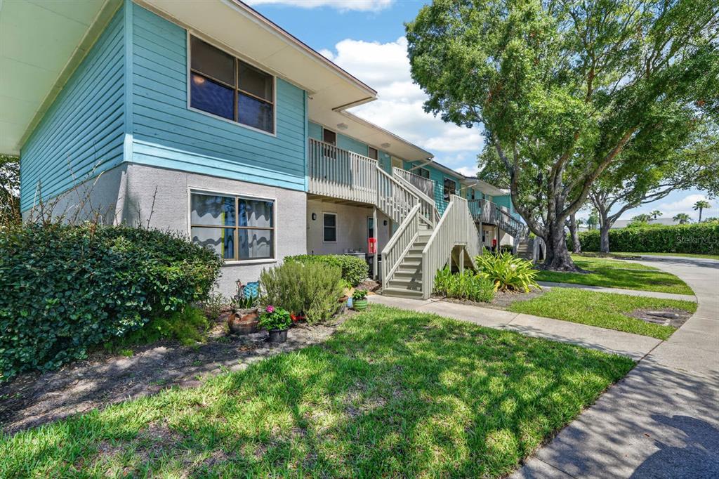 A two-story apartment building with light blue siding, a wooden staircase, and surrounding landscaping — 650 W POPE ROAD UNIT 249, ST AUGUSTINE BEACH, FL