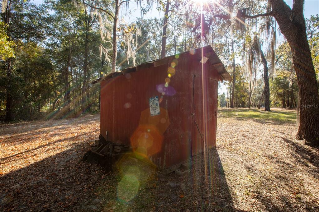 A red wooden shed stands in a wooded area covered with fallen leaves — 730+732 STATE ROAD 26, MELROSE, FL