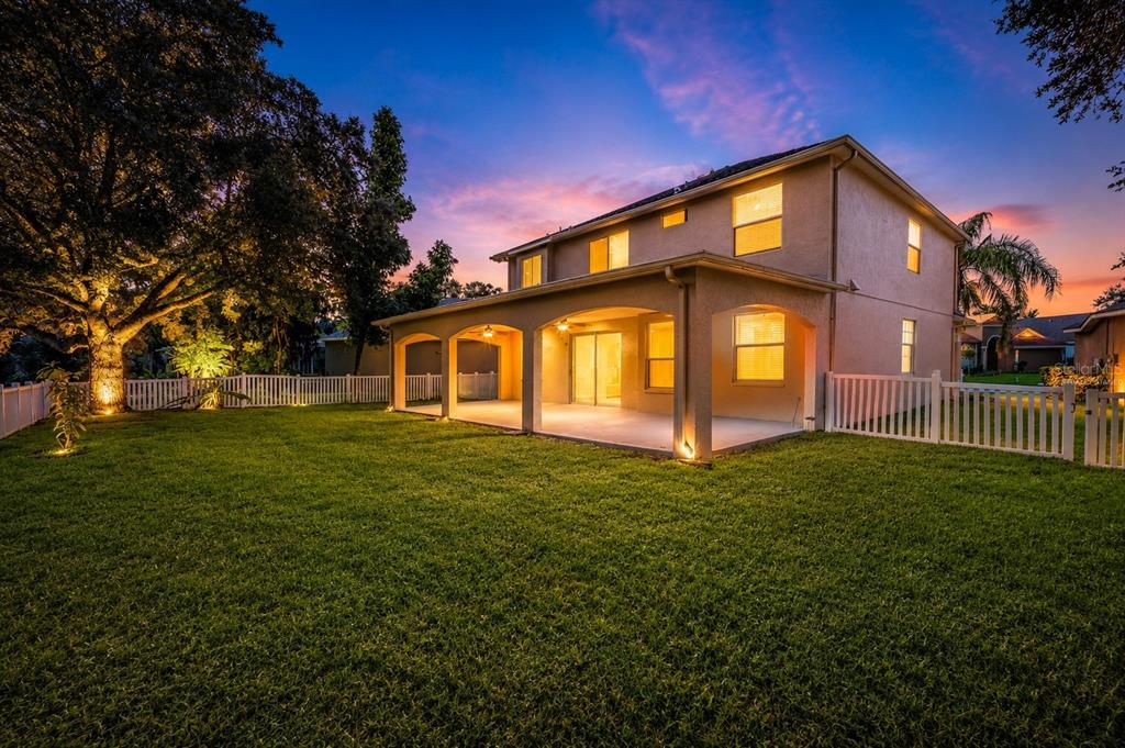 A two-story house with a covered back patio and a white vinyl fenced yard — 4716 MAPLETREE LOOP, WESLEY CHAPEL, FL