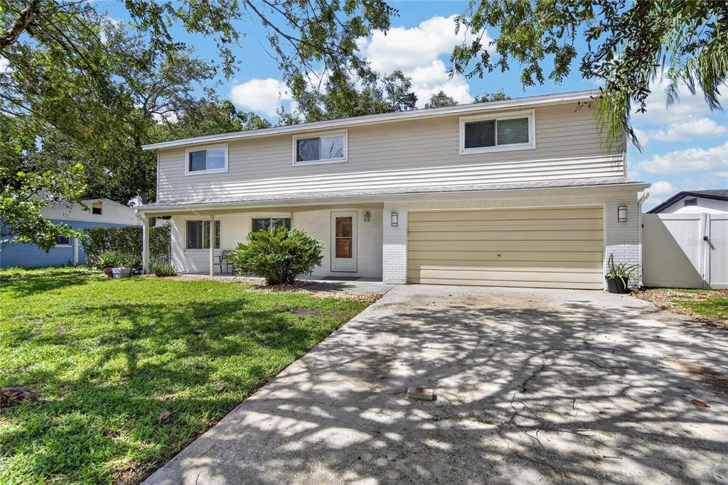A two-story house with beige siding, a two-car garage, and a concrete driveway — 10718 DRUMMOND RD, TAMPA, FL