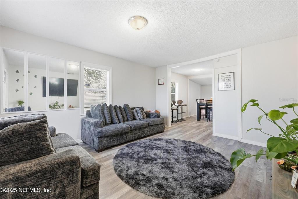 A living room features gray sofas, a circular shag rug, and light wood-look flooring — 1305 MELSON AVENUE, JACKSONVILLE, FL