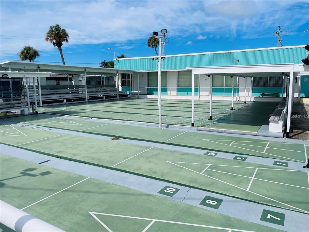 An outdoor shuffleboard court with painted markings sits in front of a teal building — 163 NEW YORK STREET, PALMETTO, FL