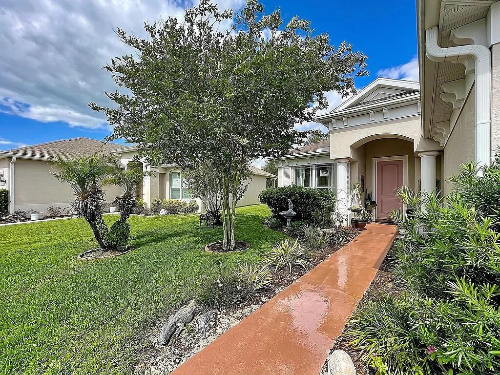 A walkway leads to the pink front door of a house with a landscaped yard — 14530 BALLOCH DRIVE, HUDSON, FL