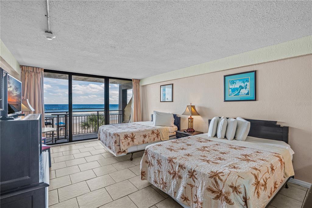 A hotel room features two beds, tile flooring, and a balcony overlooking the ocean — 2301 S ATLANTIC AVENUE UNIT 235, DAYTONA BEACH SHORES, FL