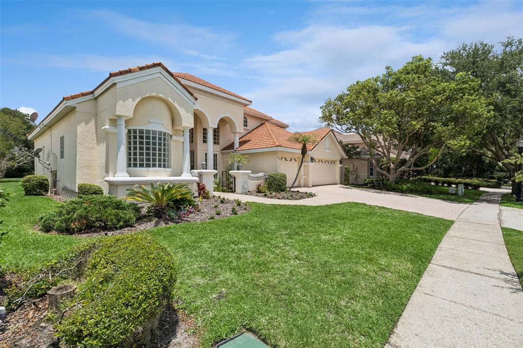A two-story stucco house with a tile roof, arched entryway, and a paved driveway — 8814 PHILLIPS BAY DRIVE, ORLANDO, FL