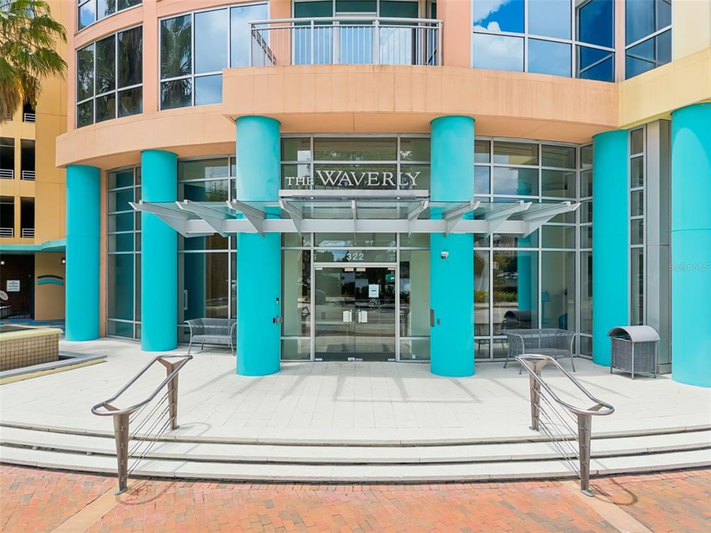 The exterior entrance of a modern building features turquoise columns and a glass canopy — 322 E CENTRAL BOULEVARD UNIT 1107, ORLANDO, FL