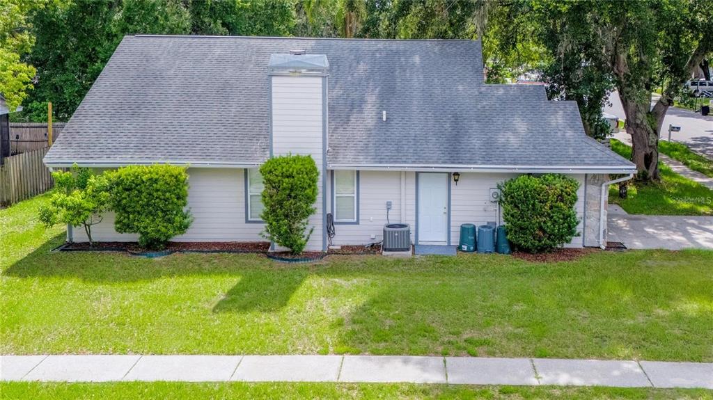 The exterior of a single-story house features light-colored siding, a gray shingled roof, and landscaping — 5116 PLANTATION DRIVE, HOLIDAY, FL