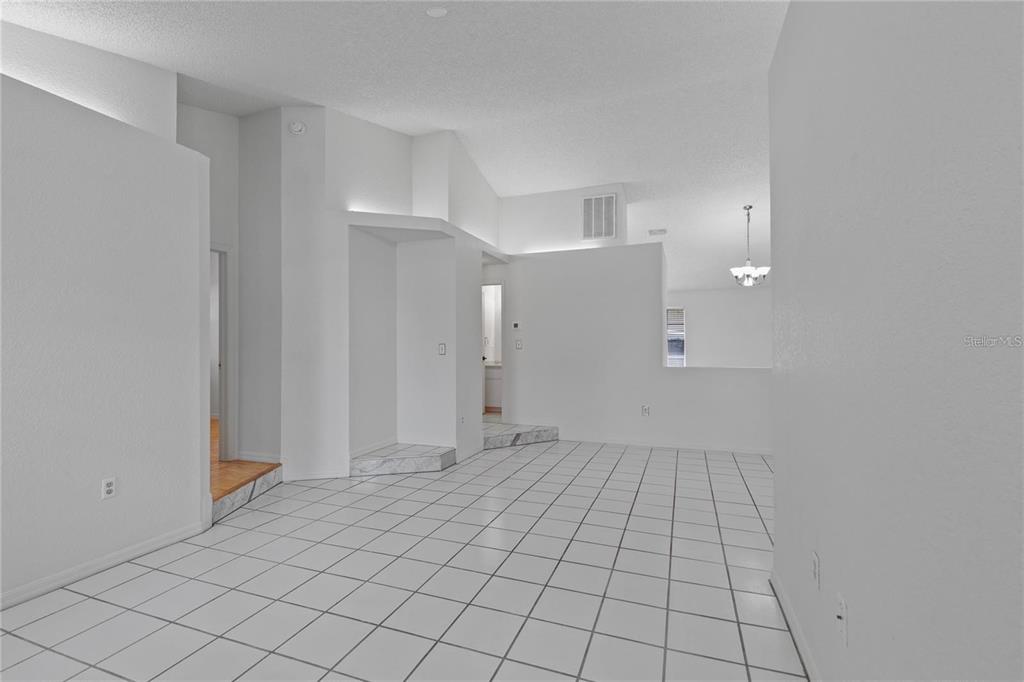 A bright, white-walled room features white tiled flooring and a raised area with steps — 5116 PLANTATION DRIVE, HOLIDAY, FL