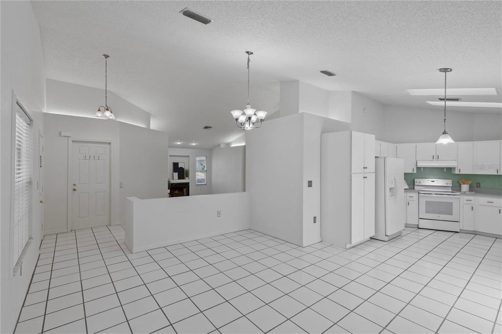 A bright kitchen and dining area with white cabinets, white appliances, and white tile flooring — 5116 PLANTATION DRIVE, HOLIDAY, FL
