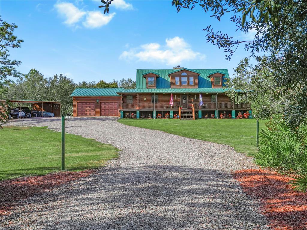 A two-story log cabin home features a green metal roof and a gravel driveway — 1894 R E BYRD ROAD, FROSTPROOF, FL