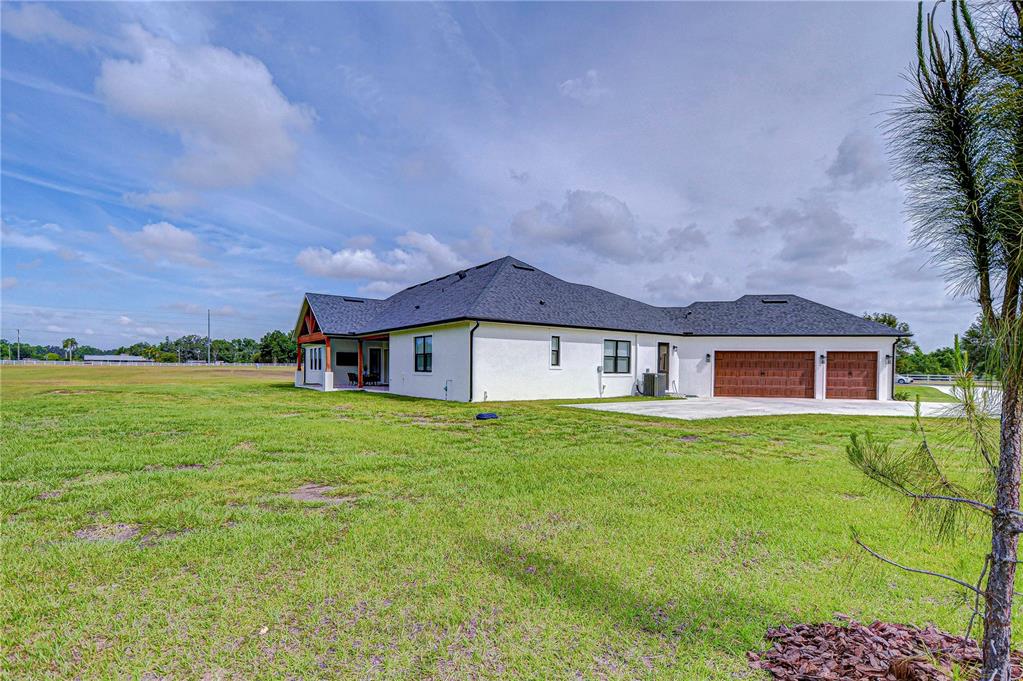 The exterior of a white single-story house with a dark roof and a three-car garage — 111 ALAFIA ESTATES LANE, LITHIA, FL