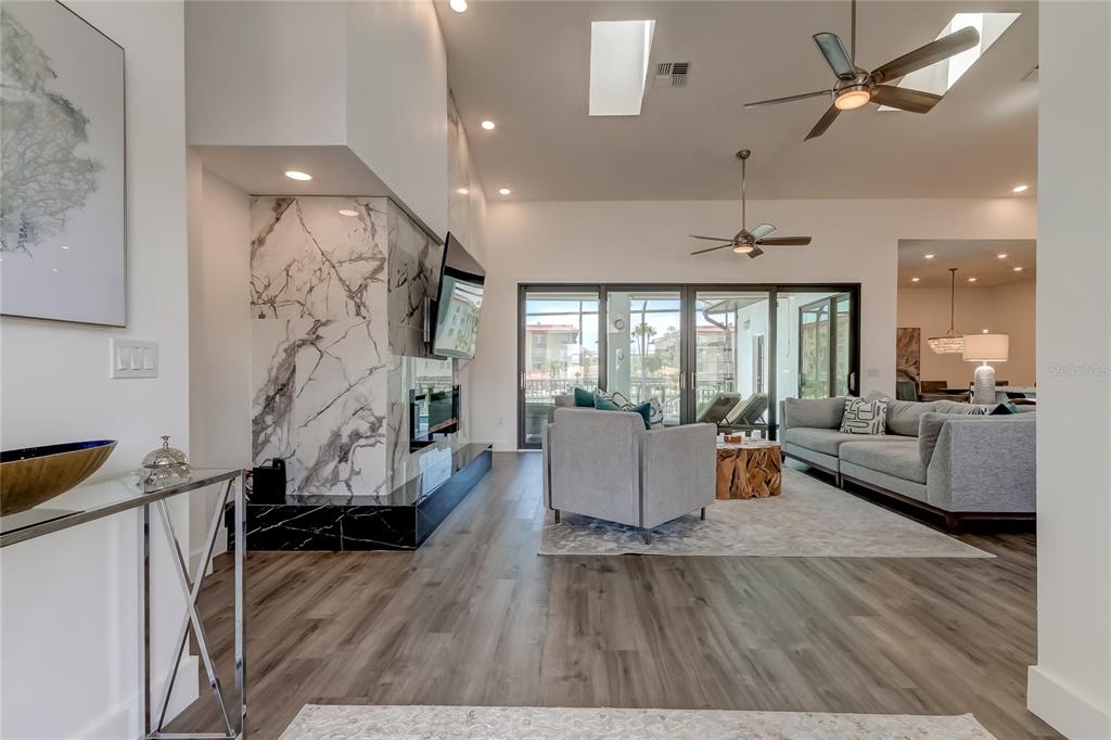 A modern kitchen features a large marble waterfall island, white cabinetry, and light wood flooring — 112 LEEWARD ISLAND, CLEARWATER, FL