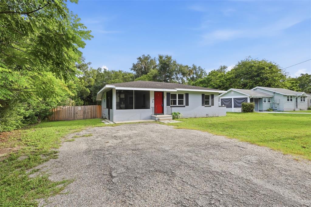A kitchen with wooden cabinets, tile flooring, and a pass-through window to an adjacent room — 320 W GRAVES AVENUE, ORANGE CITY, FL
