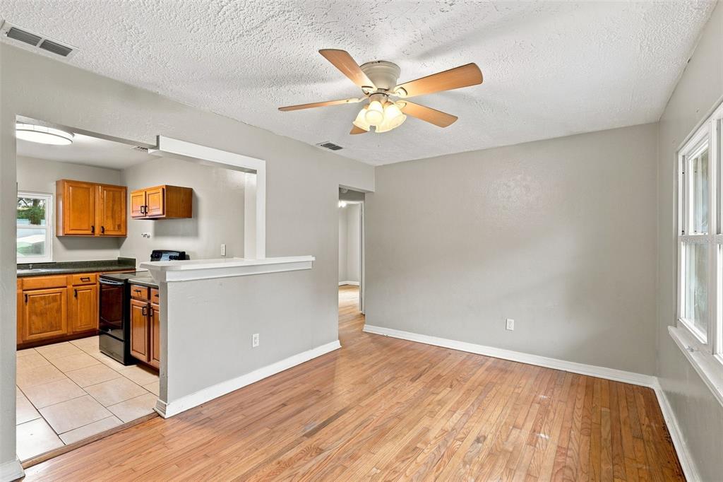 An empty room features hardwood floors, light-colored walls, a ceiling fan, and two windows — 320 W GRAVES AVENUE, ORANGE CITY, FL