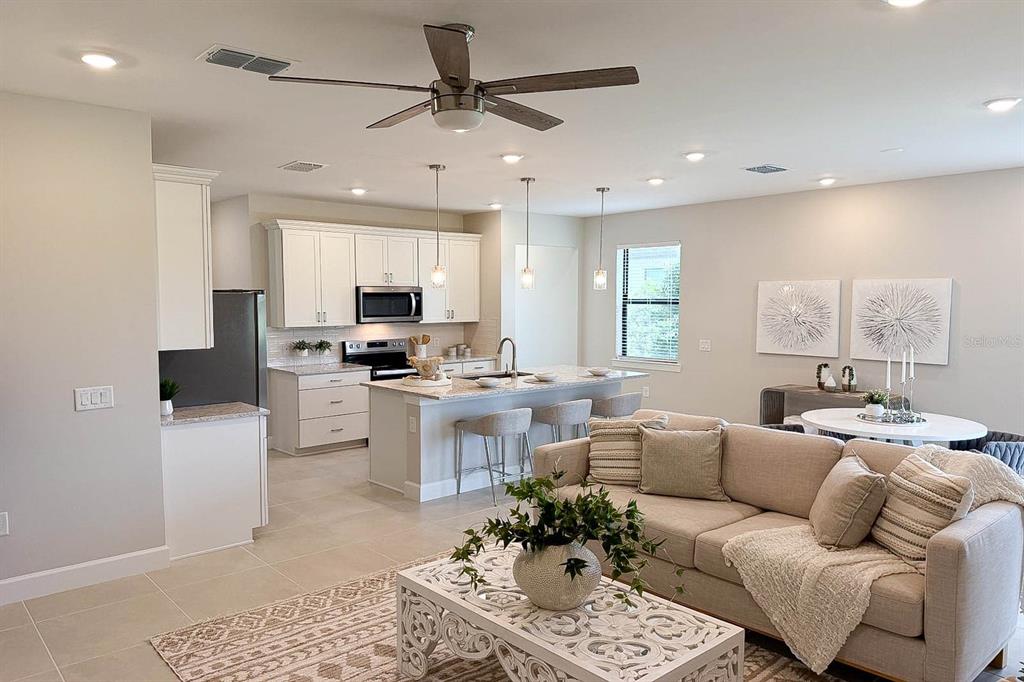 An open-concept living room and kitchen with light tile floors and white cabinetry — 5811 SILVERSIDE PINE COURT, LAKEWOOD RANCH, FL