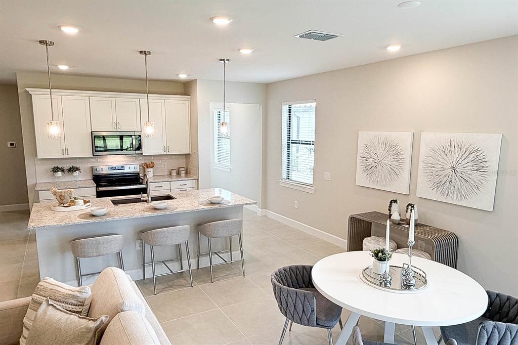 An open-concept kitchen and living area with light tile flooring and white cabinetry — 5811 SILVERSIDE PINE COURT, LAKEWOOD RANCH, FL