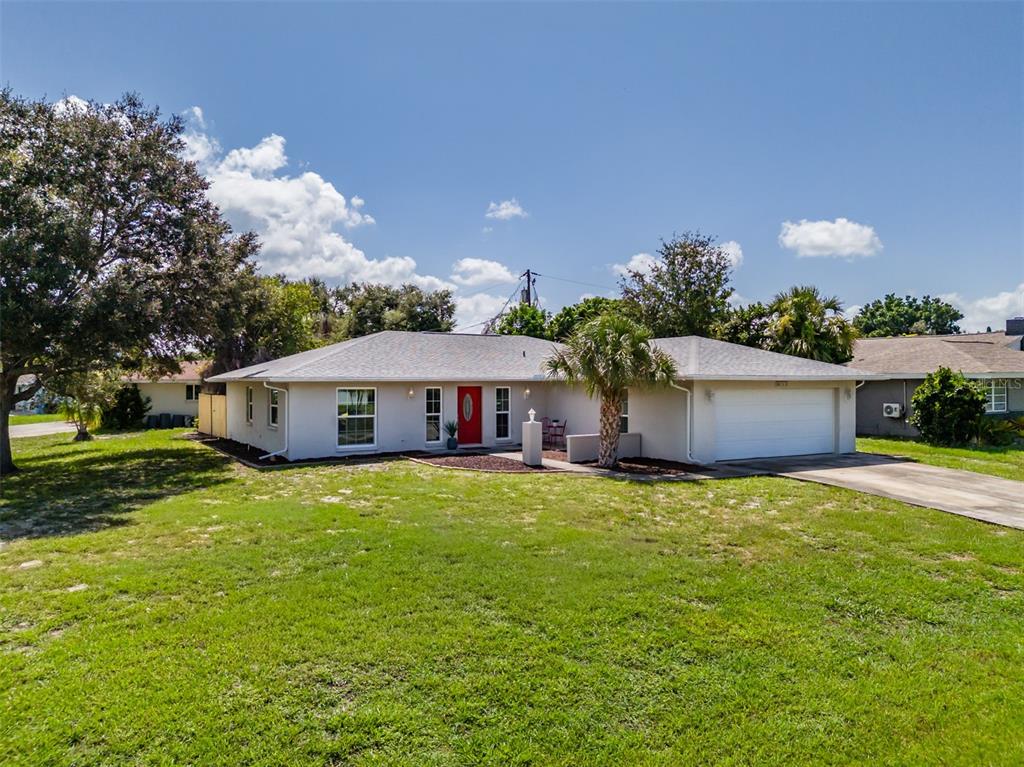 A single-story house with a white exterior, a red front door, and an attached garage — 6711 CONETTA DRIVE, SARASOTA, FL