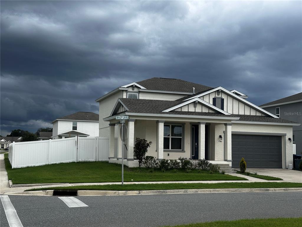 A two-story suburban house with a white fence, a front porch, and a garage — 7580 SW 63RD LANE ROAD, OCALA, FL