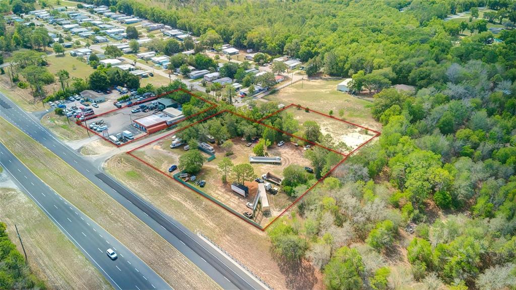 An aerial view shows a fenced lot with several vehicles and trailers near a highway — 29114 CORTEZ BOULEVARD, BROOKSVILLE, FL