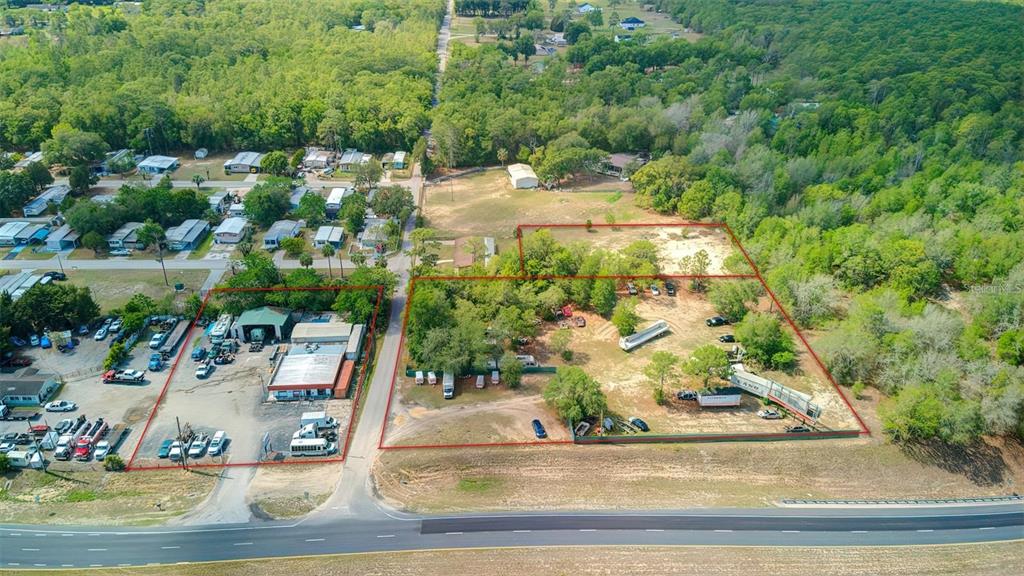 An aerial view shows two adjacent commercial lots with buildings and vehicles near a highway — 29114 CORTEZ BOULEVARD, BROOKSVILLE, FL