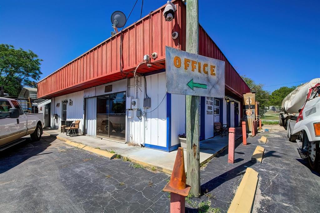 An exterior view of a commercial building with a red metal roof and office signage — 29114 CORTEZ BOULEVARD, BROOKSVILLE, FL
