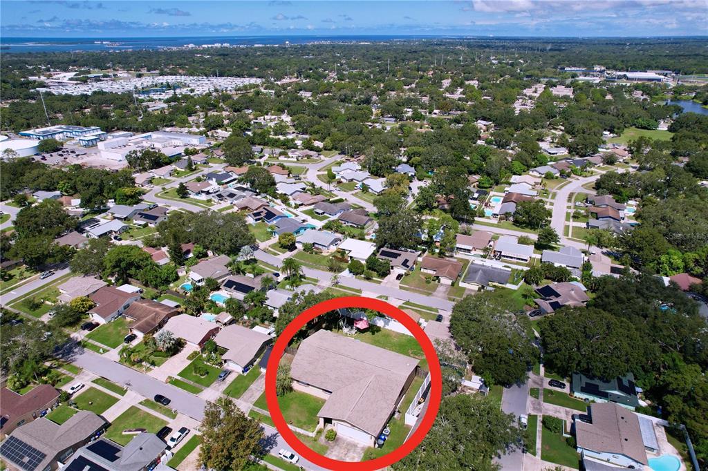 An aerial view of a single-story suburban house with a tan roof and attached garage — 1622 DALE CIRCLE S, DUNEDIN, FL