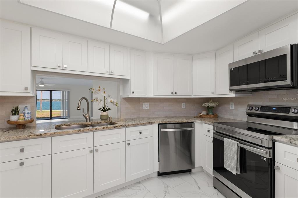 A kitchen with white cabinets, stainless steel appliances, granite countertops, and a view of water — 7540 SUNSHINE SKYWAY LANE S UNIT T35, ST PETERSBURG, FL