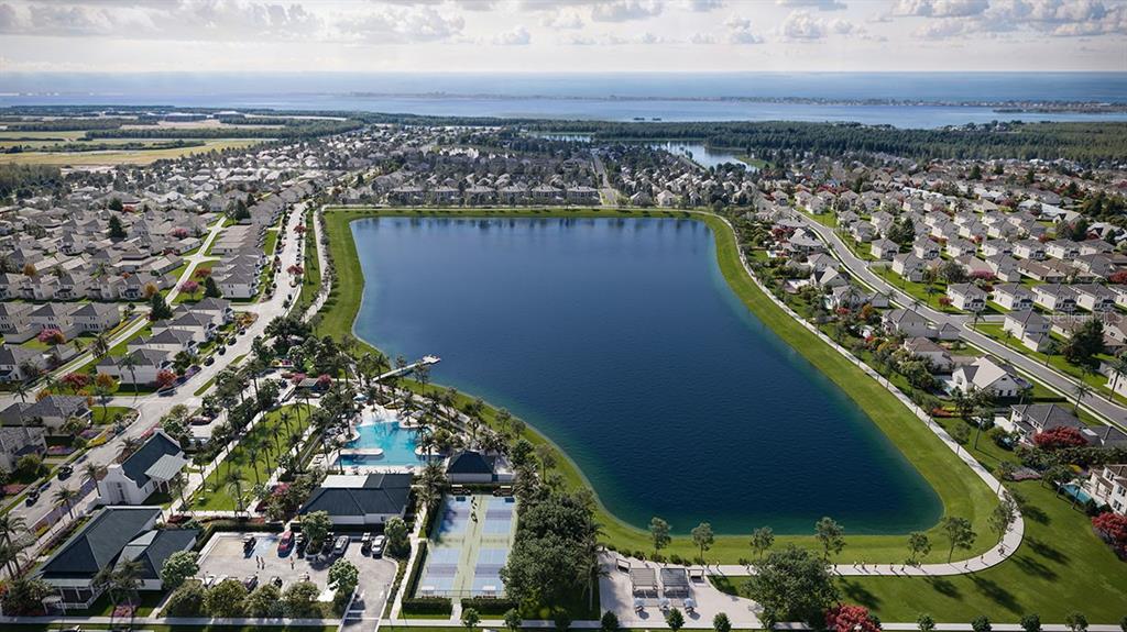 An aerial view shows a large lake surrounded by residential homes, a pool, and courts — 7808 LAKE FLORES AVENUE, BRADENTON, FL