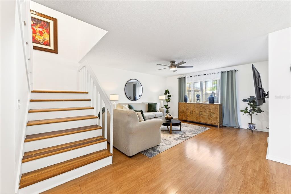 The exterior of a two-story townhouse complex features yellow siding, green hedges, and concrete walkways — 2218 MCMAHON COURT UNIT 1038, ORLANDO, FL