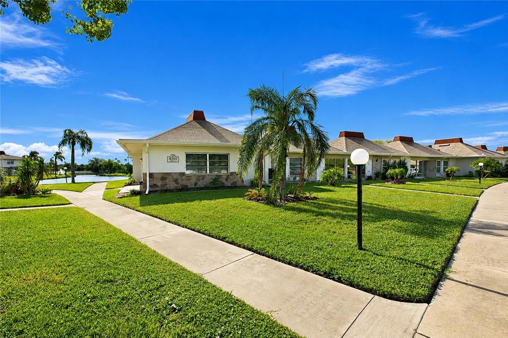 A single-story residential building with a stone facade and a palm tree on a lawn — 4344 TAHITIAN GARDENS CIRCLE UNIT D, HOLIDAY, FL