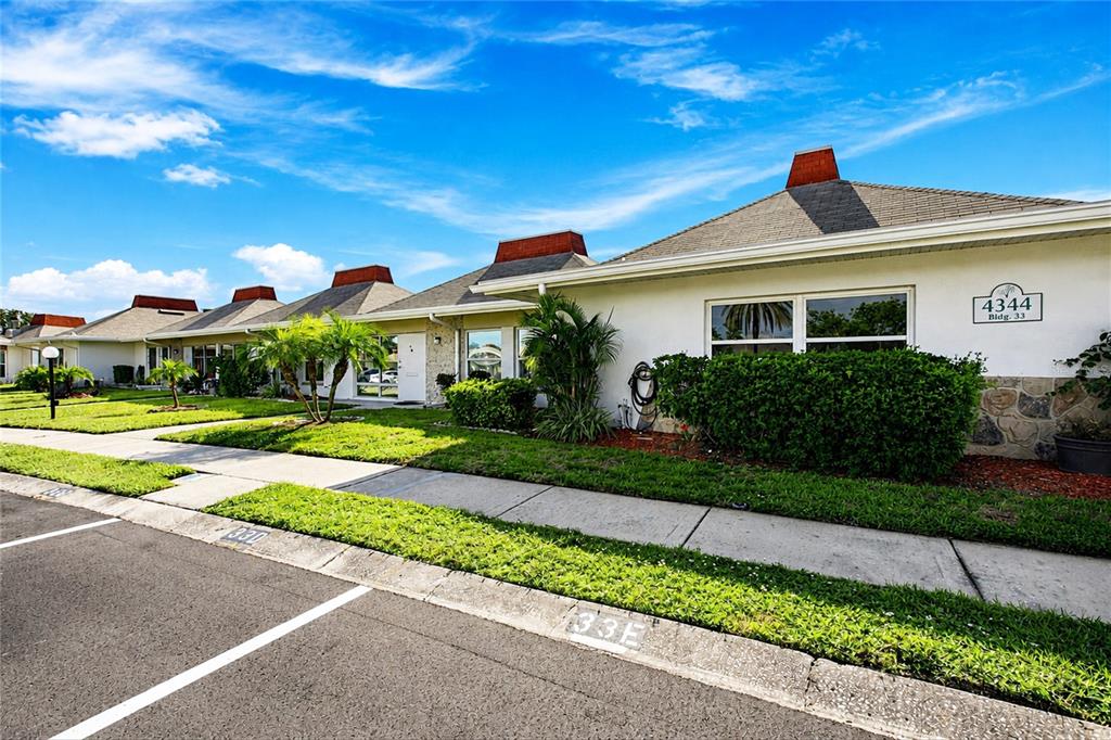 A row of single-story residential buildings with white stucco walls and dark shingled roofs — 4344 TAHITIAN GARDENS CIRCLE UNIT D, HOLIDAY, FL