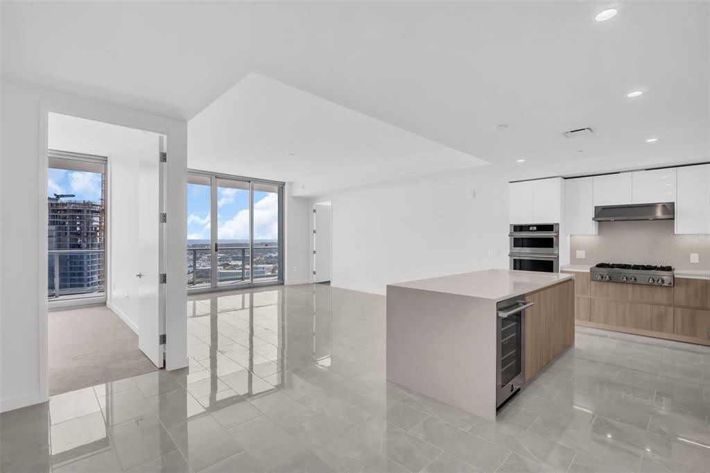 A modern kitchen with a central island and light tile floors opens to a living area — 400 CENTRAL AVENUE UNIT 2605, ST PETERSBURG, FL