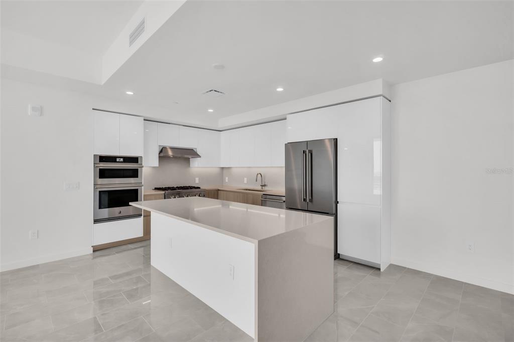 A modern kitchen features white cabinetry, stainless steel appliances, a center island, and tile flooring — 400 CENTRAL AVENUE UNIT 2605, ST PETERSBURG, FL