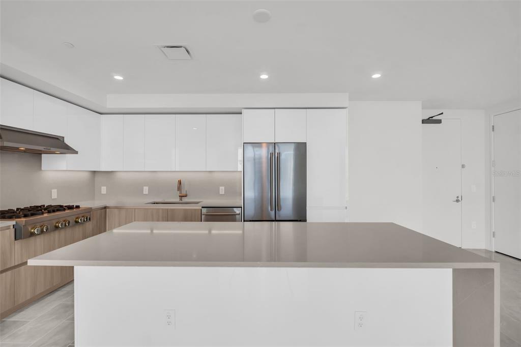 A modern kitchen features white cabinetry, a large quartz island, and stainless steel appliances — 400 CENTRAL AVENUE UNIT 2605, ST PETERSBURG, FL